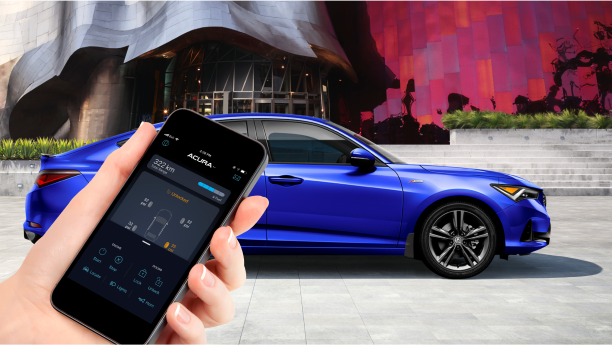 In the foreground, a hand is holding a smartphone displaying the AcuraLink app/À l’avant-plan, une main tient un téléphone intelligent affichant l’application AcuraLink.