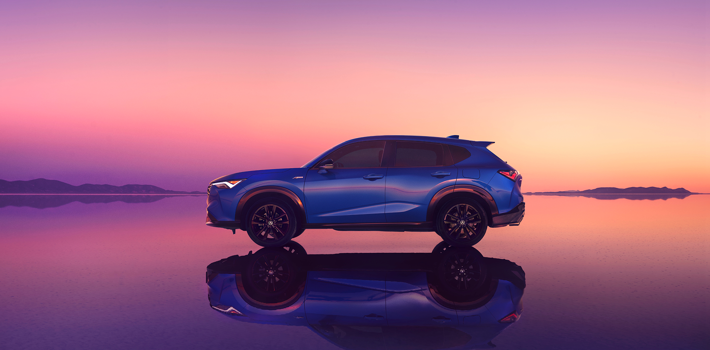 Acura ADX vu de côté devant un coucher de soleil rose.