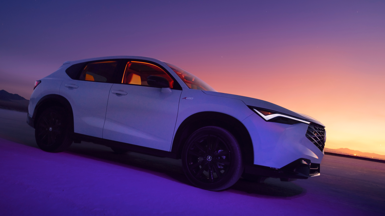 Acura ADX blanc vu de côté avec un coucher de soleil au loin.