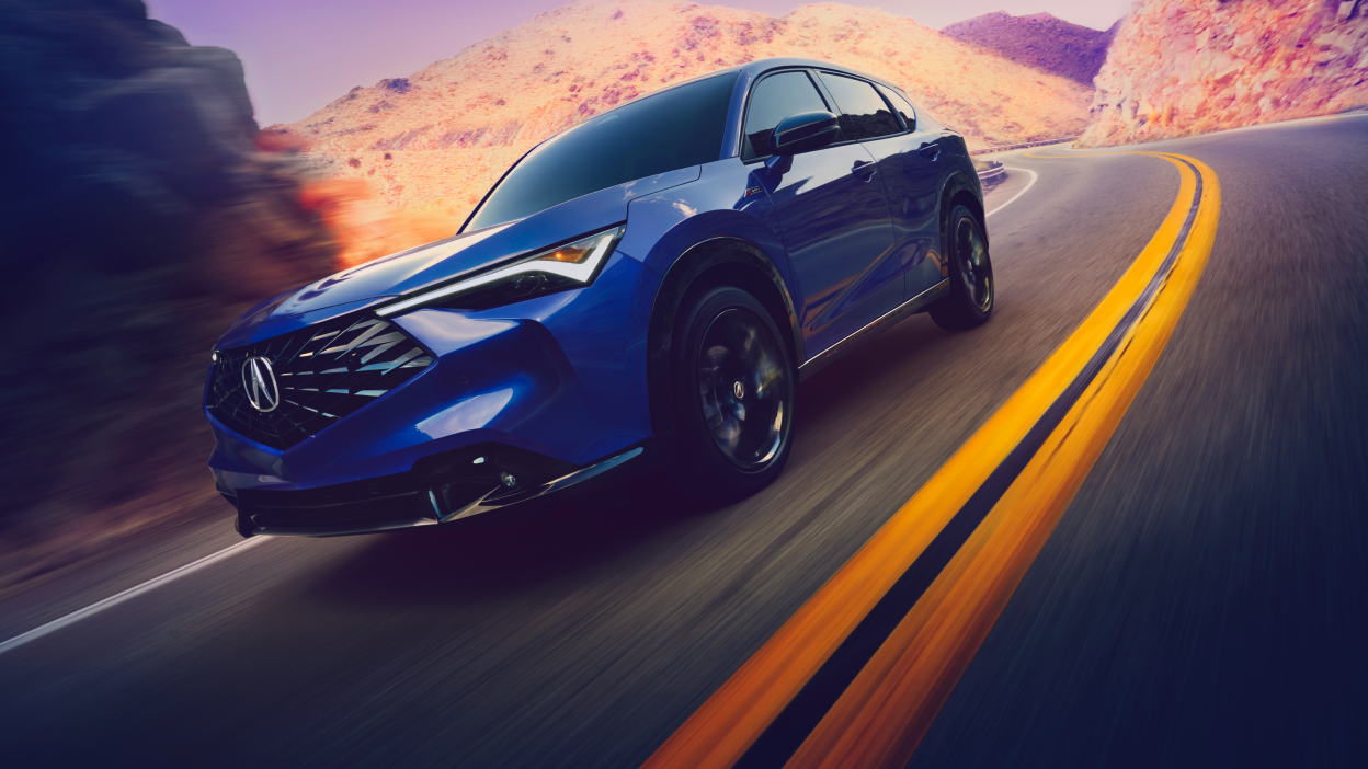 Side view of an Acura ADX turning the corner on a mountain highway. 