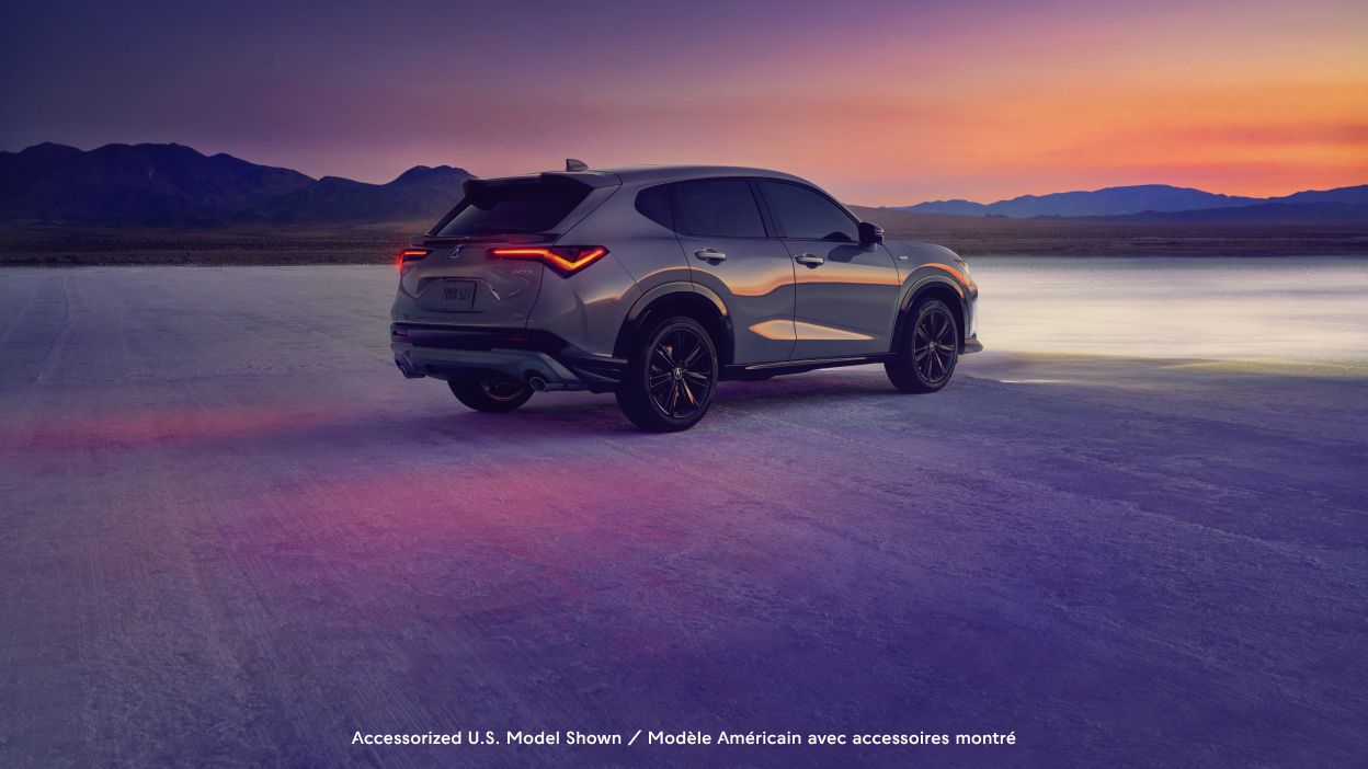 Plan grand angle d’un Acura ADX vu de l’arrière devant un coucher de soleil.