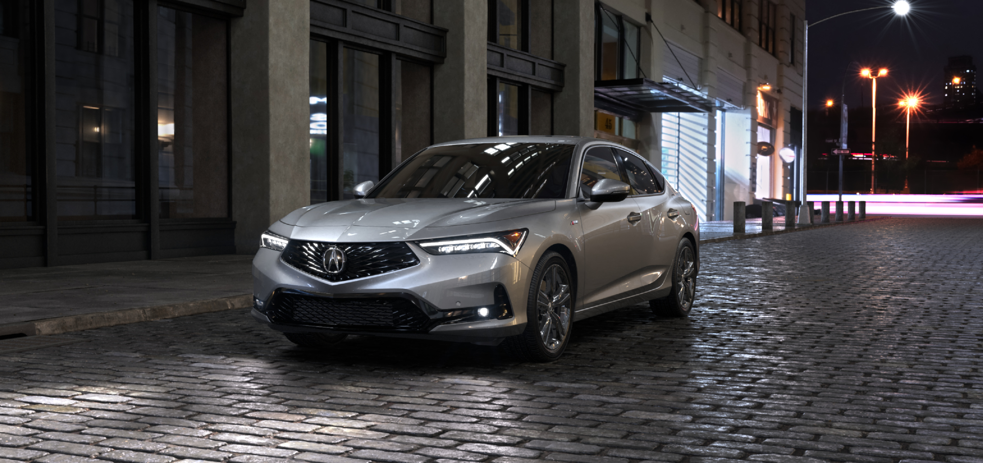 3/4 driver-side front view of 2025 silver Integra parked on a street in the city at night