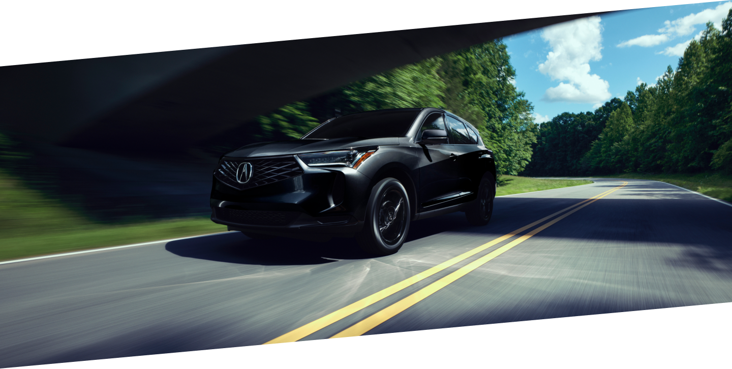 Plan de trois quarts latéral d’un RDX noir circulant sur une autoroute de campagne pendant la journée.