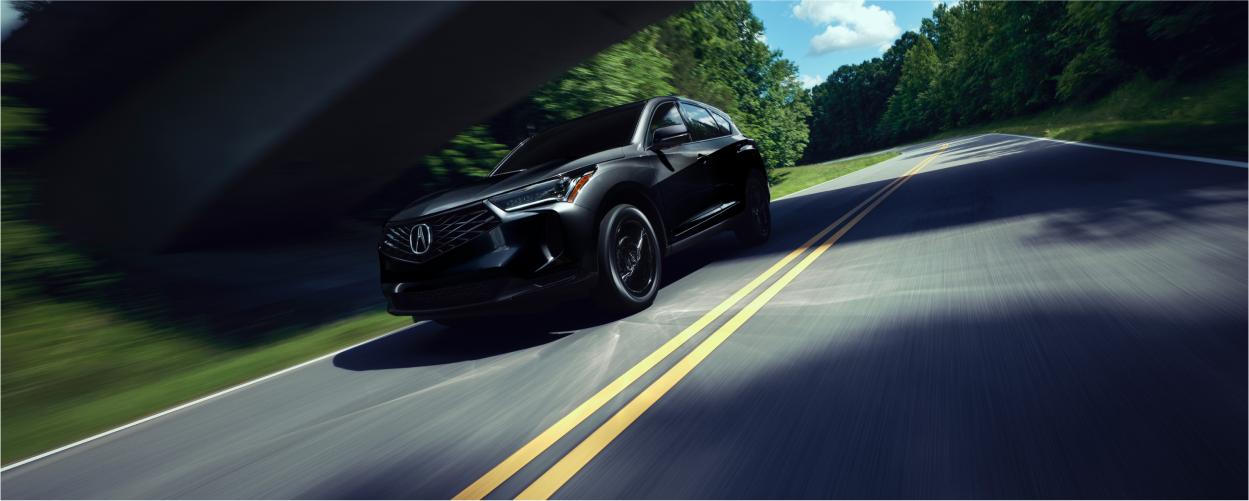 Plan de trois quarts latéral d’un RDX noir circulant sur une autoroute de campagne pendant la journée.