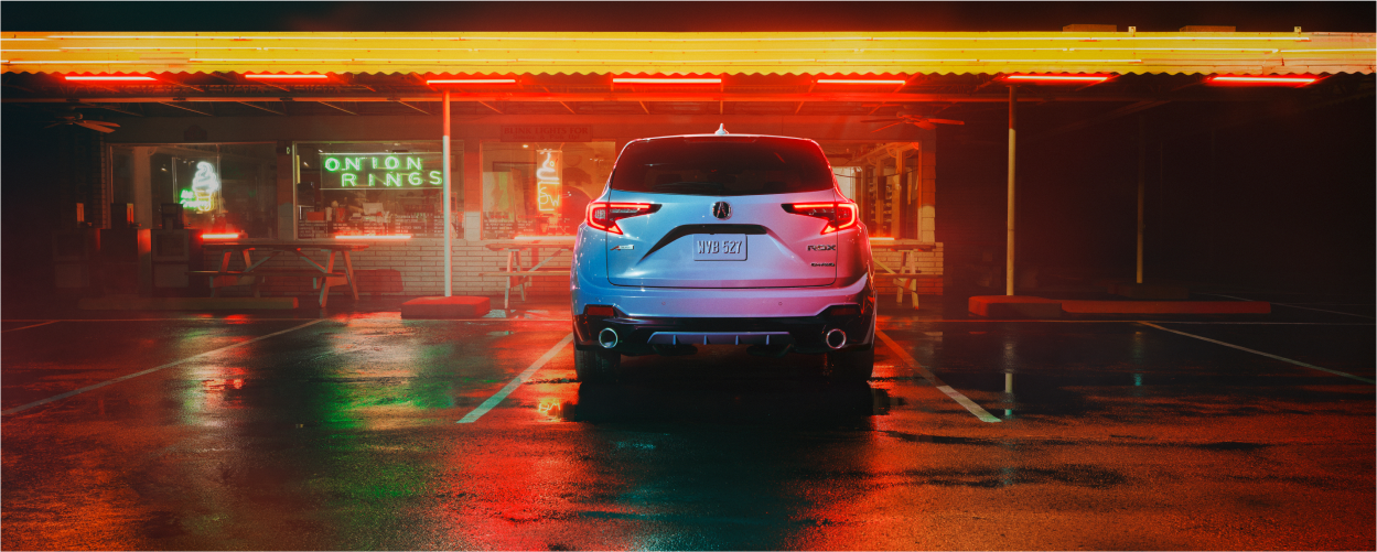 Vue 3/4 avant d’un RDX bleu circulant sur une route de terre battue.