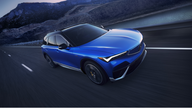 Plan de trois quarts avant en plongée d’un ZDX bleu circulant sur une autoroute désertique au crépuscule.