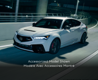 Plan de trois quarts latéral d’une Integra Type S blanche effectuant un virage sur une bretelle d’autoroute la nuit.