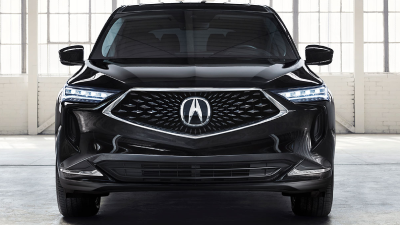 Front-facing shot of a black Acura MDX parked in a large, empty white garage space featuring loft-style windows and white brick walls. Vue avant d’un Acura MDX noir stationné dans un grand garage blanc vide muni de fenêtres de style loft et de murs de briques blanches.