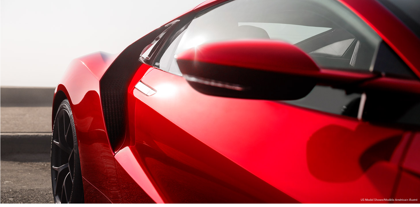 Close-up of the passenger side door and rear fender of a red Acura NSX Supercar. Gros plan de la porte du côté passager et de l’aile arrière d’une supervoiture Acura NSX rouge.