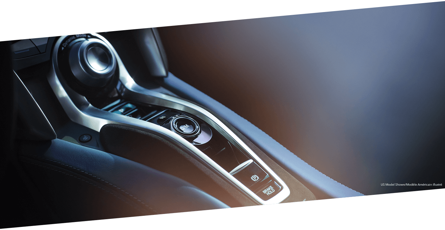 Close-up of the centre console in an Acura NSX showcasing the electric drive mode functionality. Gros plan de la console centrale d’une Acura NSX qui souligne le mode de conduite électrique.